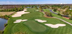 Golfové hřiště s greenem, bunkery a jezírkem za slunečného dne