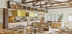 Interiér světlé restaurace s dřevěnými trámy a stolky s židlemi