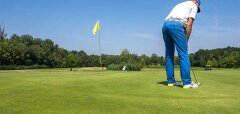 Golfista puttuje na golfovém hřišti za slunečného dne