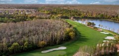 Letecký pohled na golfové hřiště obklopené lesem a jezírkem