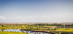 Golfové hřiště s jezírkem a zelenou krajinou za slunečného dne