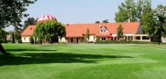 Zelené golfové hřiště s budovou a balónem v pozadí