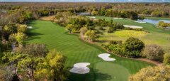 Golfové hřiště s jamkami, stromy a jezírky v pozadí