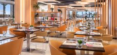 Interiér moderní restaurace s oranžovými židlemi a stolky