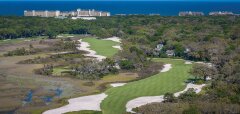 Golfové hřiště u pobřeží s budovami a oceánem v pozadí