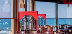 Interiér restaurace s výhledem na moře a červenými dekoracemi