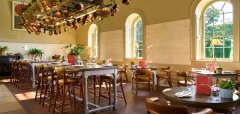 Interiér restaurace s dřevěným nábytkem a zavěšenými měděnými hrnci