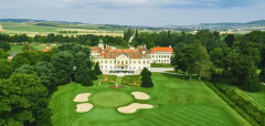 Golfové hřiště s pískovými bunkry a zámkem v pozadí