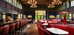 Interiér restaurace s červenými koženými sedačkami a barovými židlemi