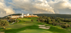 Golfové hřiště s bílými budovami a kopci v pozadí