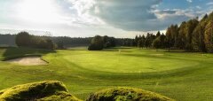Golfové hřiště s jamkou a pískovým bunkrem za slunečného dne