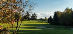 Golfové hřiště s podzimními stromy a modrou oblohou