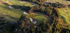 Letecký pohled na golfové hřiště obklopené stromy a lesem