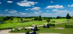 Golfové hřiště s golfovými vozíky a modrou oblohou