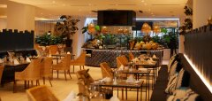 Interiér restaurace s ratanovými židlemi a dekorativními rostlinami