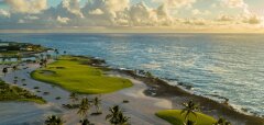 Golfové hřiště u oceánu s palmami a oblakovou oblohou