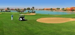 Golfista u golfového vozíku na hřišti u vody v El Gouna Golf Club