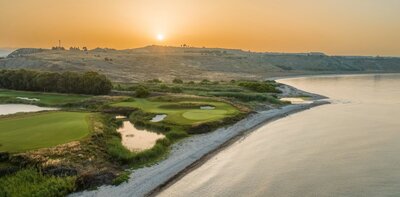 Golfové hřiště u moře s pískovým bunkrem a věží v pozadí