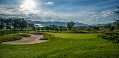 Golfové hřiště s pískovým bunkrem a stromy v pozadí