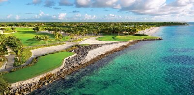 Pobřeží s golfovým hřištěm a palmami u modrého moře