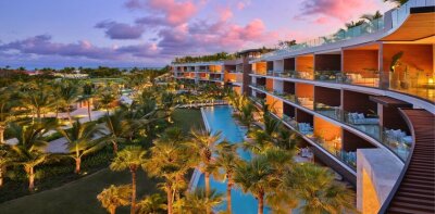 Luxusní resort s bazénem a palmami při západu slunce