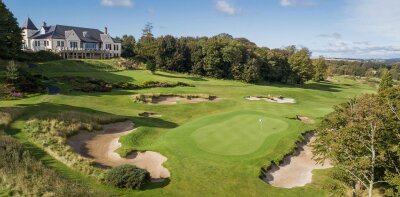 Golfové hřiště s greenem, bunkry a budovou v pozadí