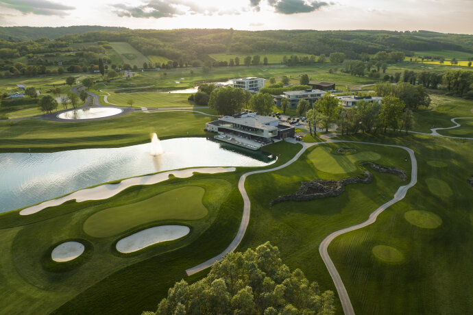 Golfové hřiště se jezírkem a budovami za soumraku