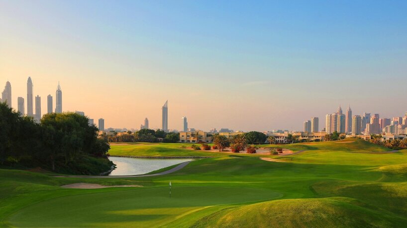 Golfové hřiště s městskou panorámou v pozadí za soumraku
