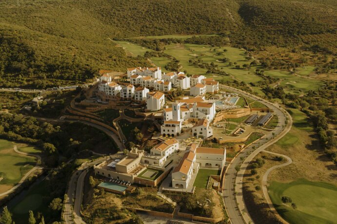 Letecký pohled na resort s bílými budovami a golfovým hřištěm v přírodě