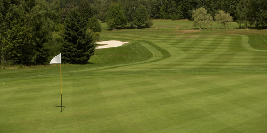 Golfové hřiště s bílou vlajkou a pískovým bunkrem
