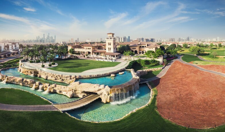 Golfové hřiště s vodopádem a budovou v pozadí Jumeirah Golf Estates