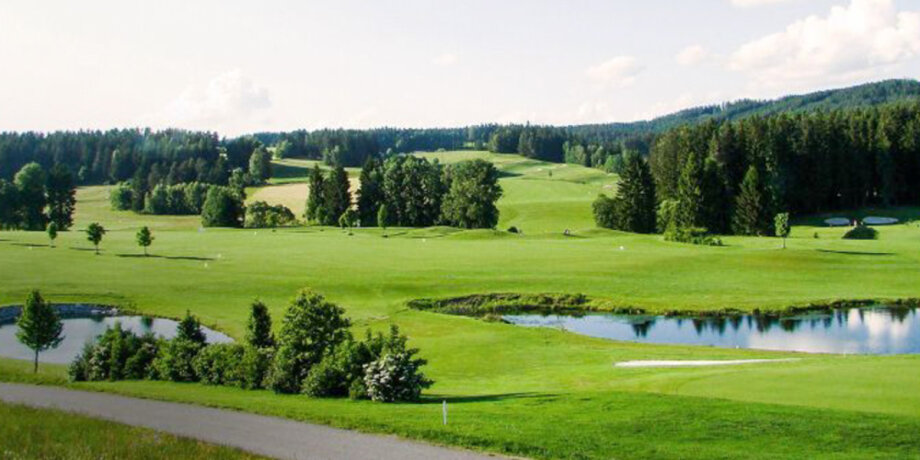 Golfové hřiště s jezírky a stromy v pozadí