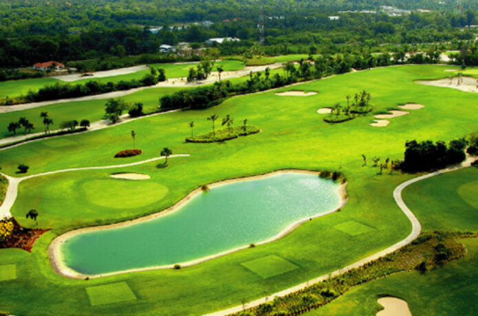 Zelené golfové hřiště s jezírkem a stromy v krajině