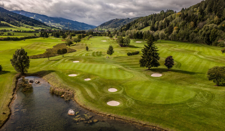 Golfové hřiště s jezírkem a okolními stromy v horské krajině