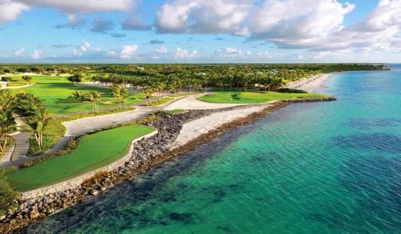 Pobřeží s golfovým hřištěm a palmami u modrého moře
