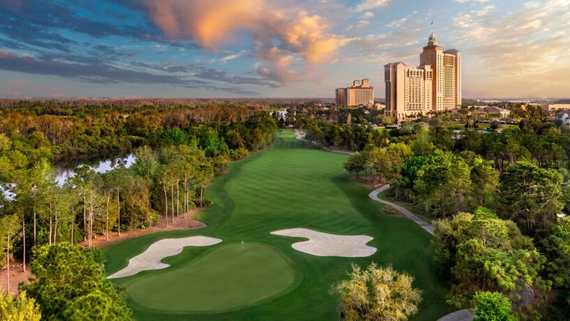 Golfové hřiště s bunkry a budovou hotelu za soumraku