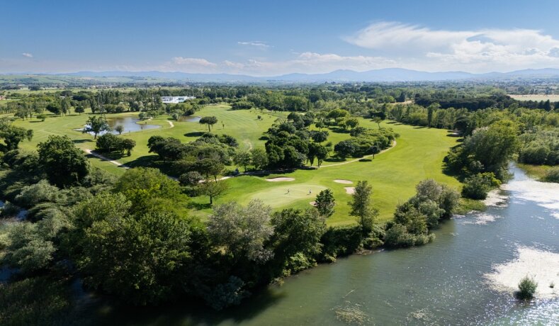 Golfové hřiště u řeky s okolní zelení a stromy