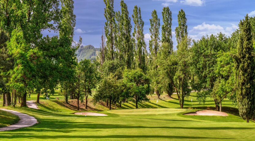 Golfové hřiště s greenem a stromy v pozadí