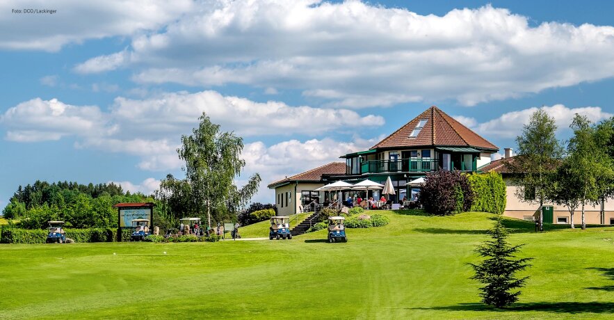 Golfové hřiště s klubovnou a golfovými vozíky na trávníku
