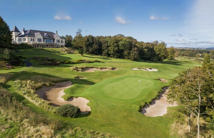 Golfové hřiště s greenem, bunkry a budovou v pozadí